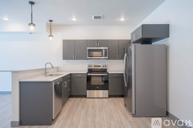 A modern kitchen with stainless steel appliances and wooden flooring.