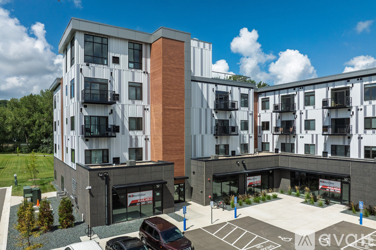 A modern apartment complex with a parking lot in front.