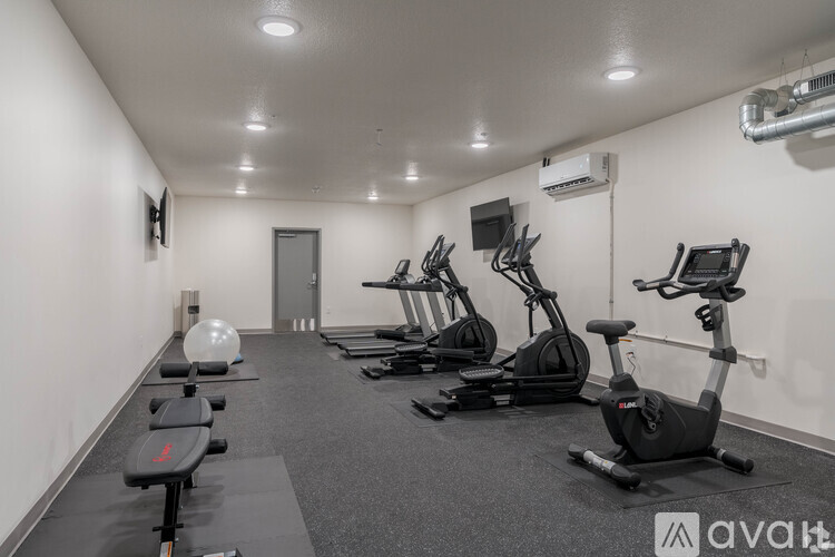 A gym with a row of exercise bikes and elliptical machines.