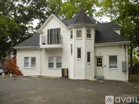 A white house with a black roof and a balcony.