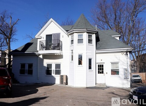 A white two-story house with a balcony on the second floor.