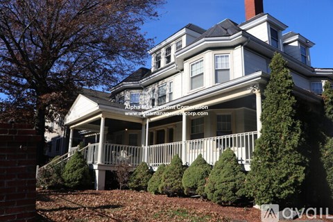 A large white house with a balcony and a sign that says "Alpha Management Corporation".
