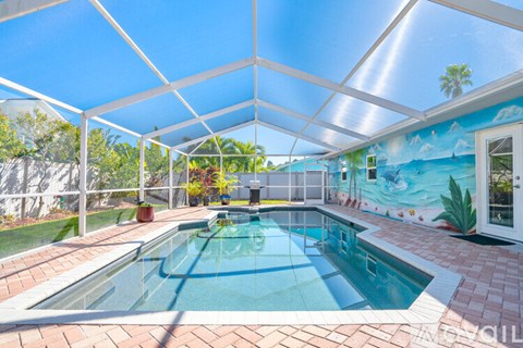 A pool inside a house with a mural on the wall.