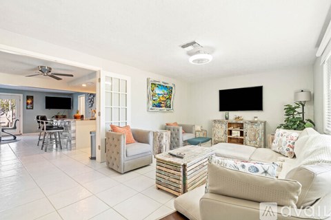 A living room with a white couch and a television on the wall.