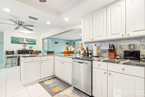 A kitchen with white cabinets and a marble countertop.