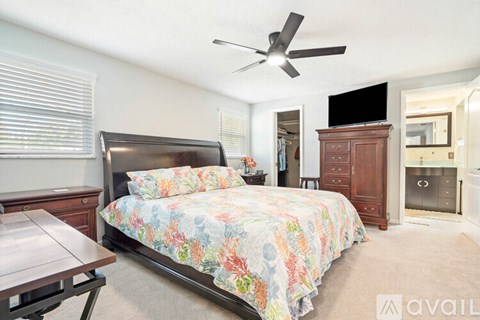 A bedroom with a large bed and a ceiling fan.