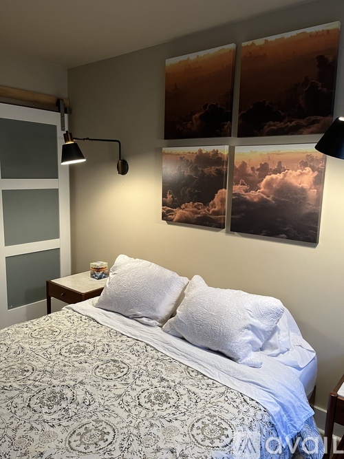 A bedroom with a bed, a nightstand, and three posters on the wall.