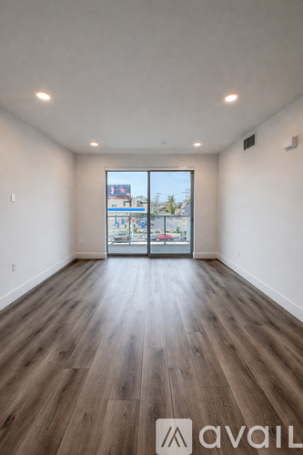 A room with wooden floors and a window overlooking a street.