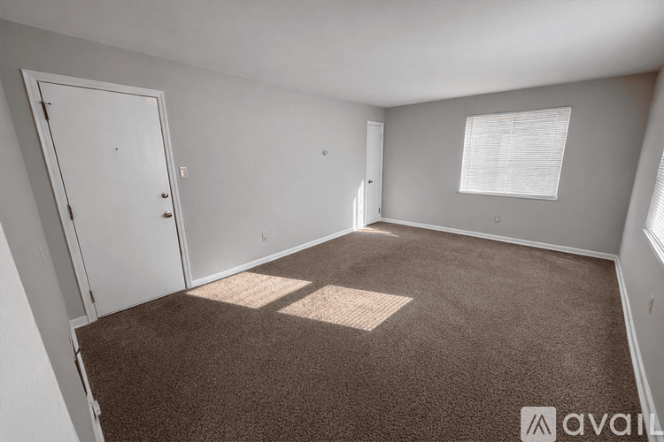 A room with a carpeted floor and a window with blinds.