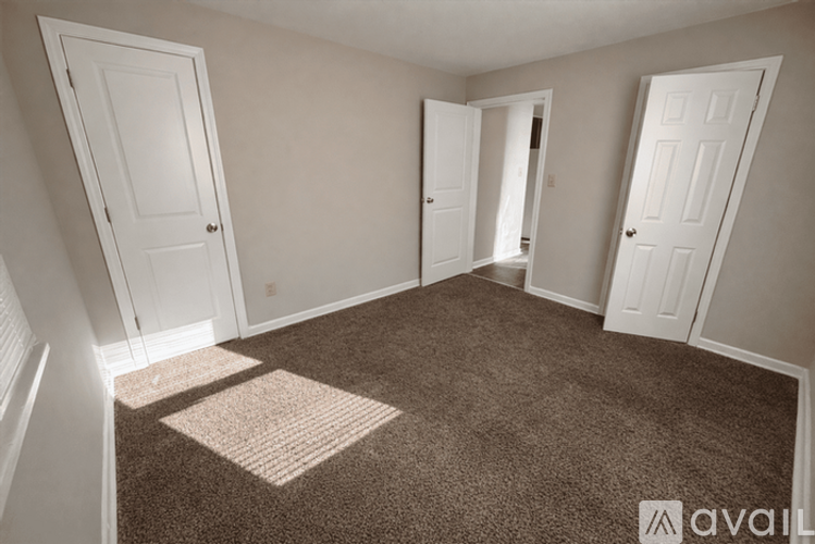 A room with carpeted floor and three doors.