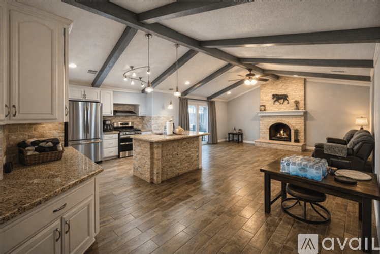 A kitchen with a stone fireplace and wooden floors.
