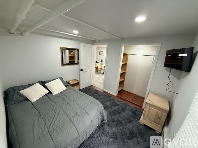 A bedroom with a bed, a dresser, and a TV.