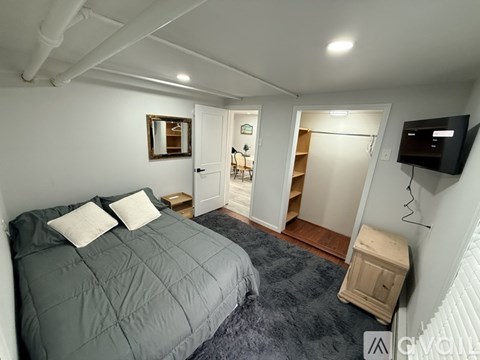 A bedroom with a bed, a dresser, and a TV.