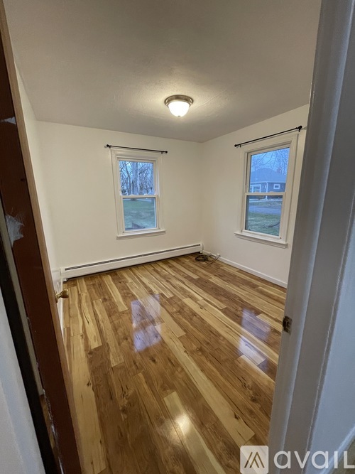 A room with wooden floors and two windows.