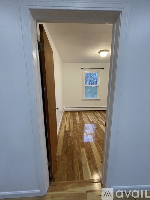 A hallway with a wooden floor and a white wall.