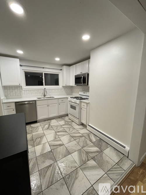 A kitchen with white cabinets and a black counter.