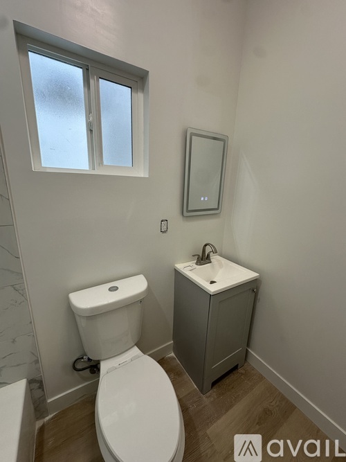 A white toilet sits next to a sink in a small bathroom.