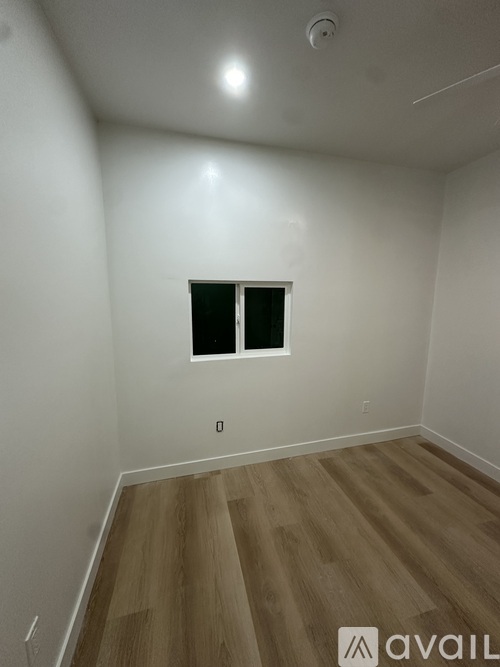 A room with a window and wooden flooring.