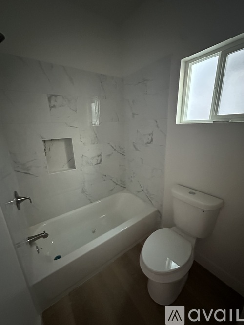 A room with a white door and a window with a fan on the ceiling.