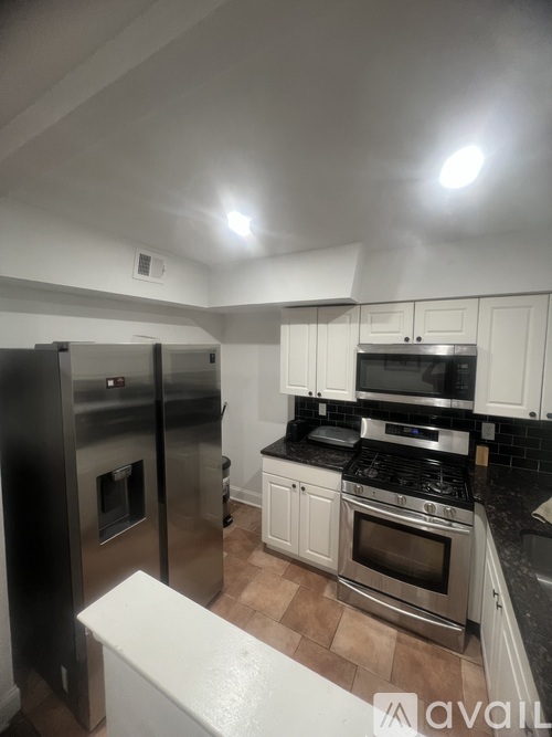 A kitchen with a stainless steel refrigerator and oven, and a black countertop.