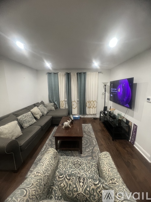A living room with a grey couch, a coffee table, and a television on the wall.