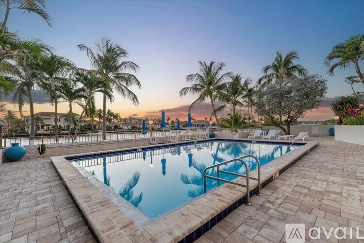 A pool surrounded by palm trees and a sunset in the background.