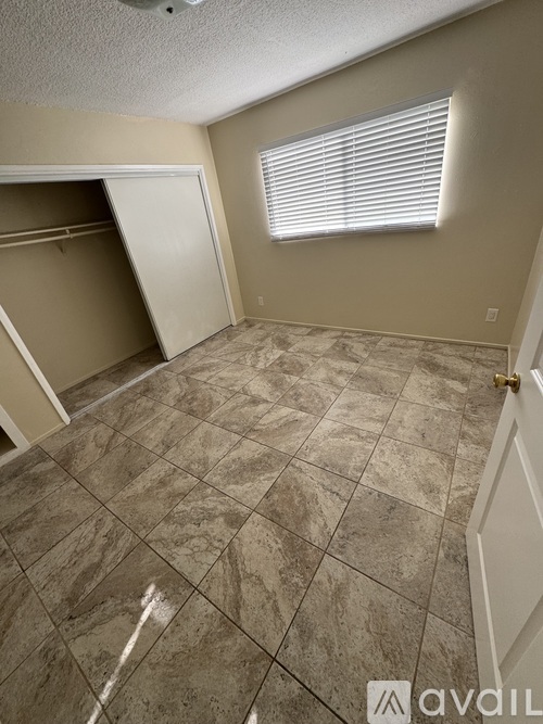 A room with tiled flooring and a window with blinds.