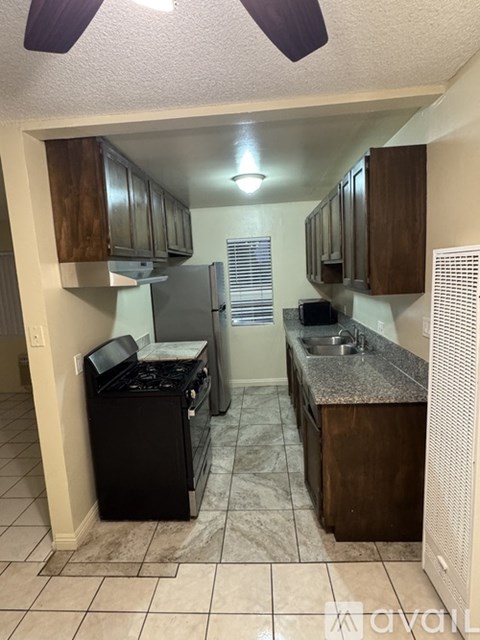 A kitchen with a black dishwasher and wooden cabinets.