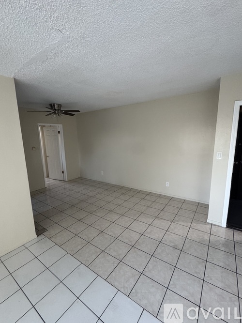 A room with a ceiling fan and tile flooring.