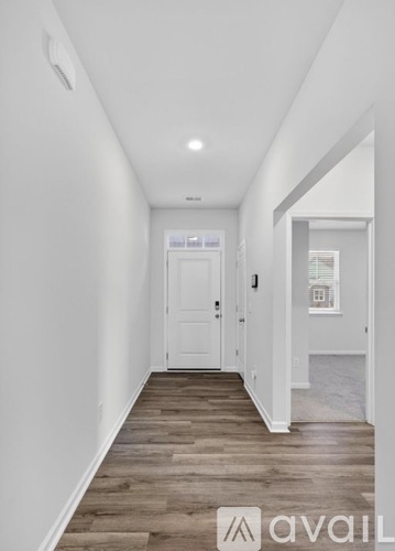 A hallway with a white door and wooden flooring.