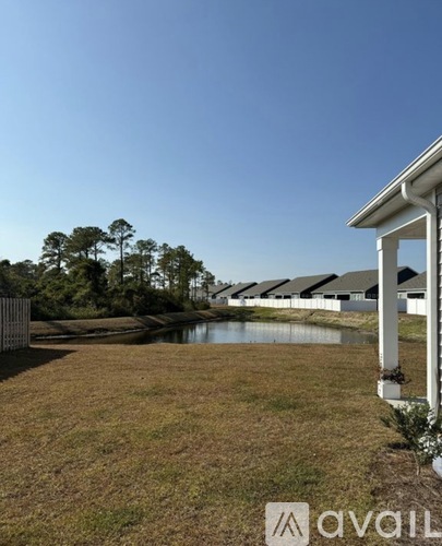 A grassy area with a pond and trees in the distance.