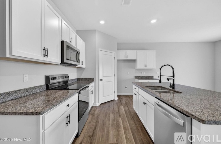 A kitchen with white cabinets and a granite countertop.