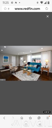 A living room with a blue couch and a white rug.