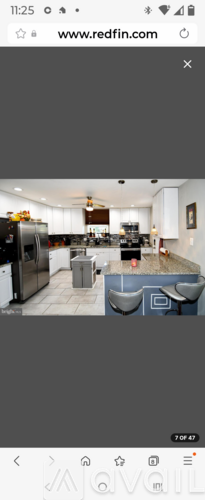 A modern kitchen with white cabinets and a black refrigerator.