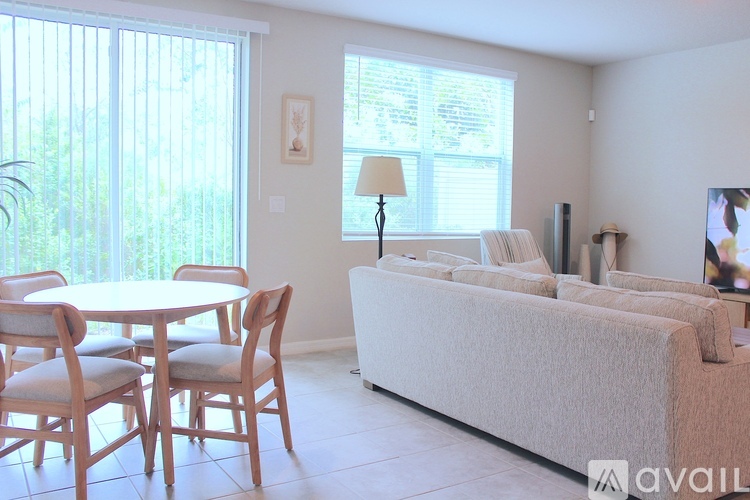 A living room with a white couch and a round wooden table.