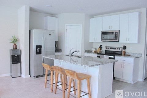 A kitchen with white cabinets and a marble countertop.