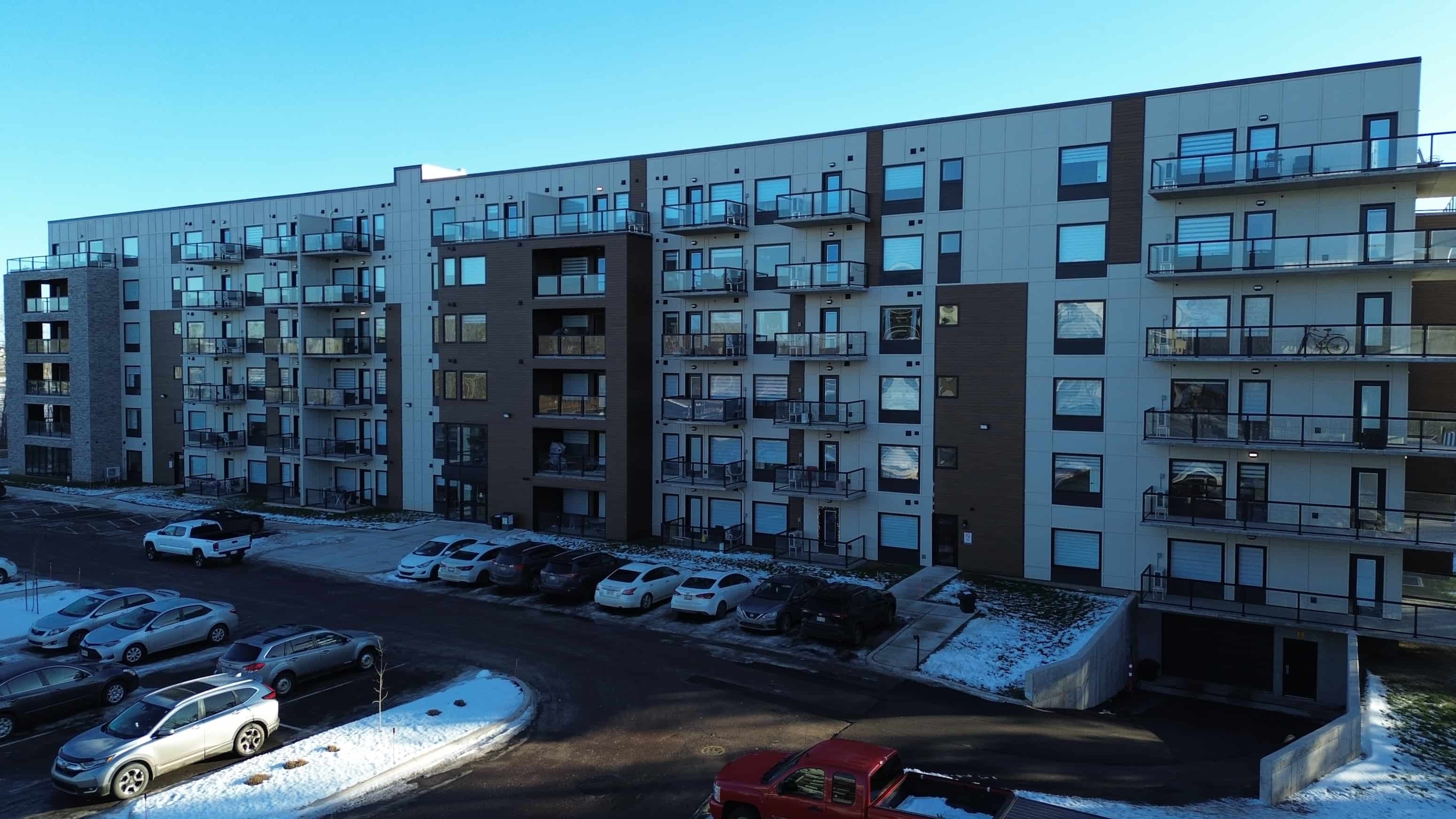A large apartment complex with a parking lot in front.