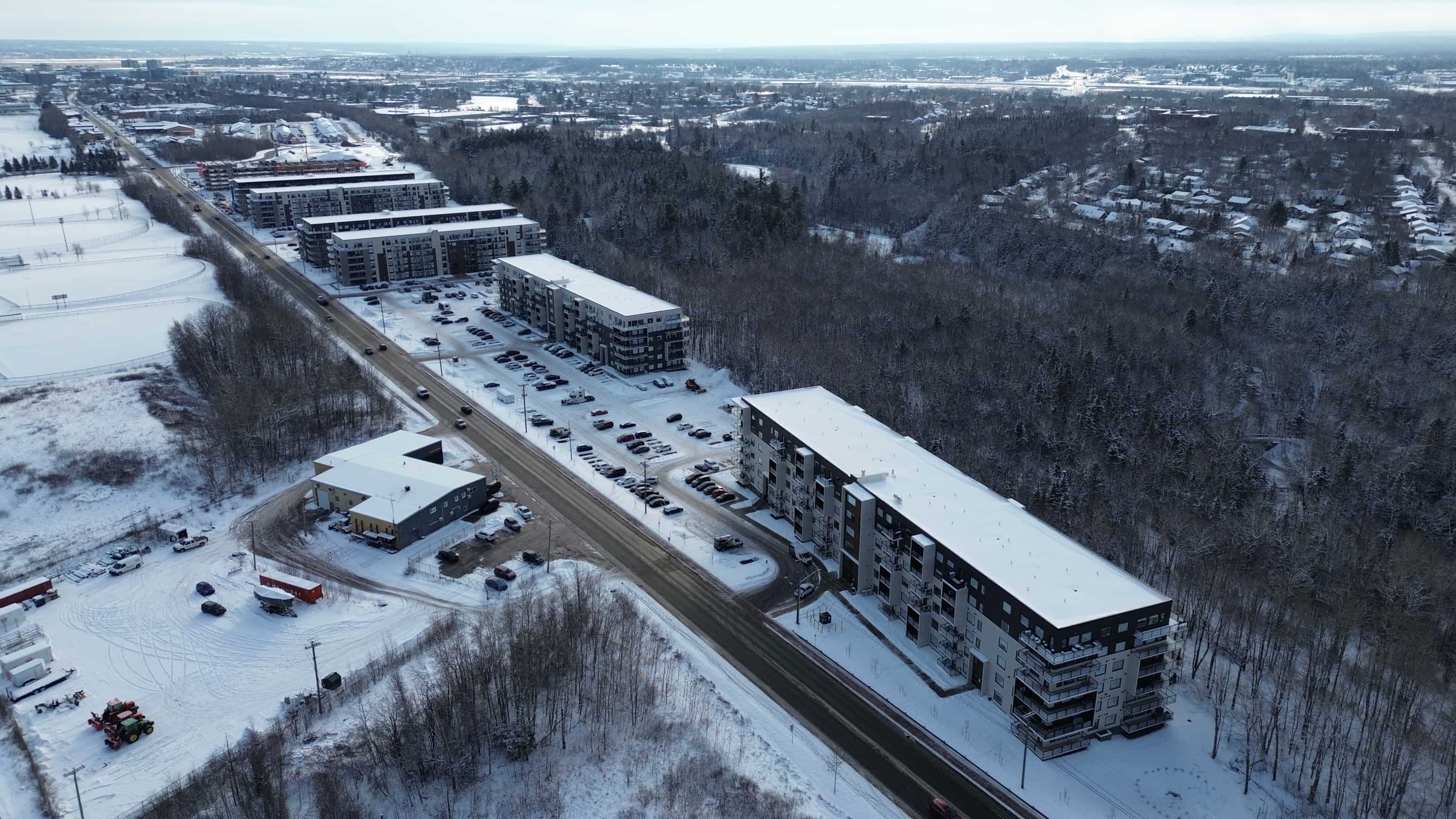 A long building with a parking lot in front of it.
