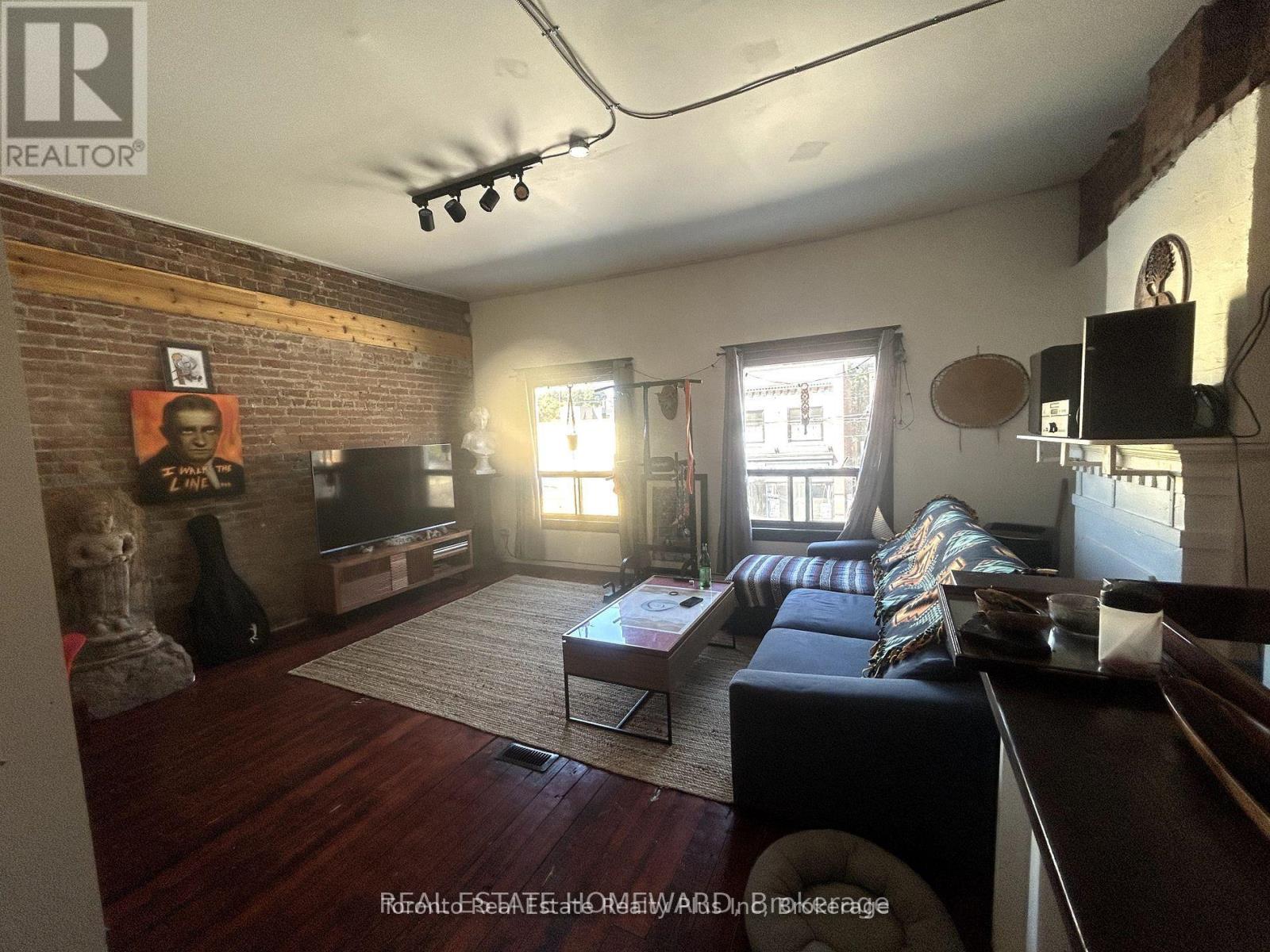 A living room with a brick wall and a flat screen TV.