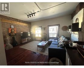 A living room with a brick wall and a flat screen TV.