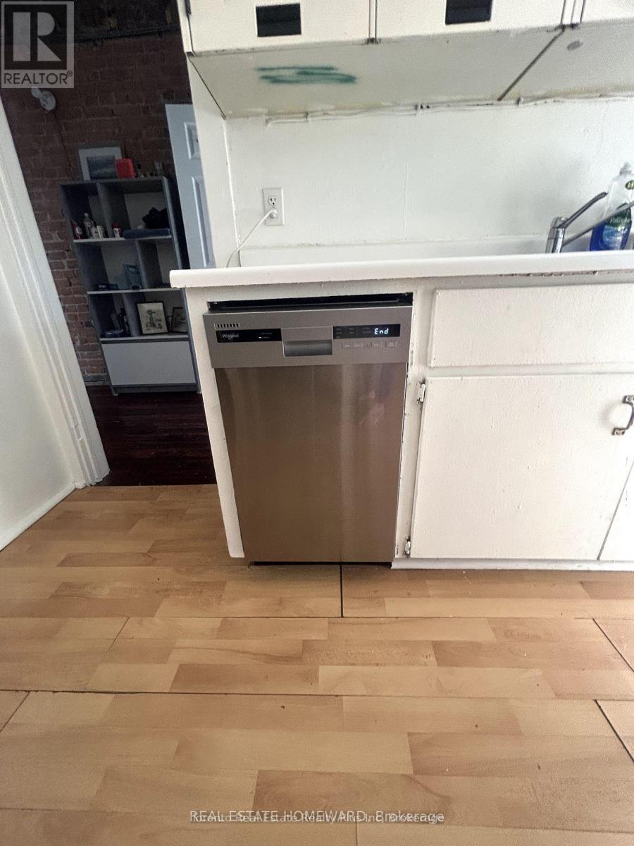 A dishwasher is in a kitchen with a white countertop and wooden flooring.