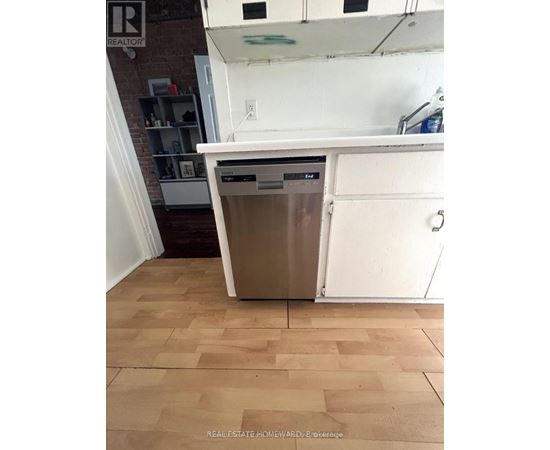 A dishwasher is in a kitchen with a white countertop and wooden flooring.