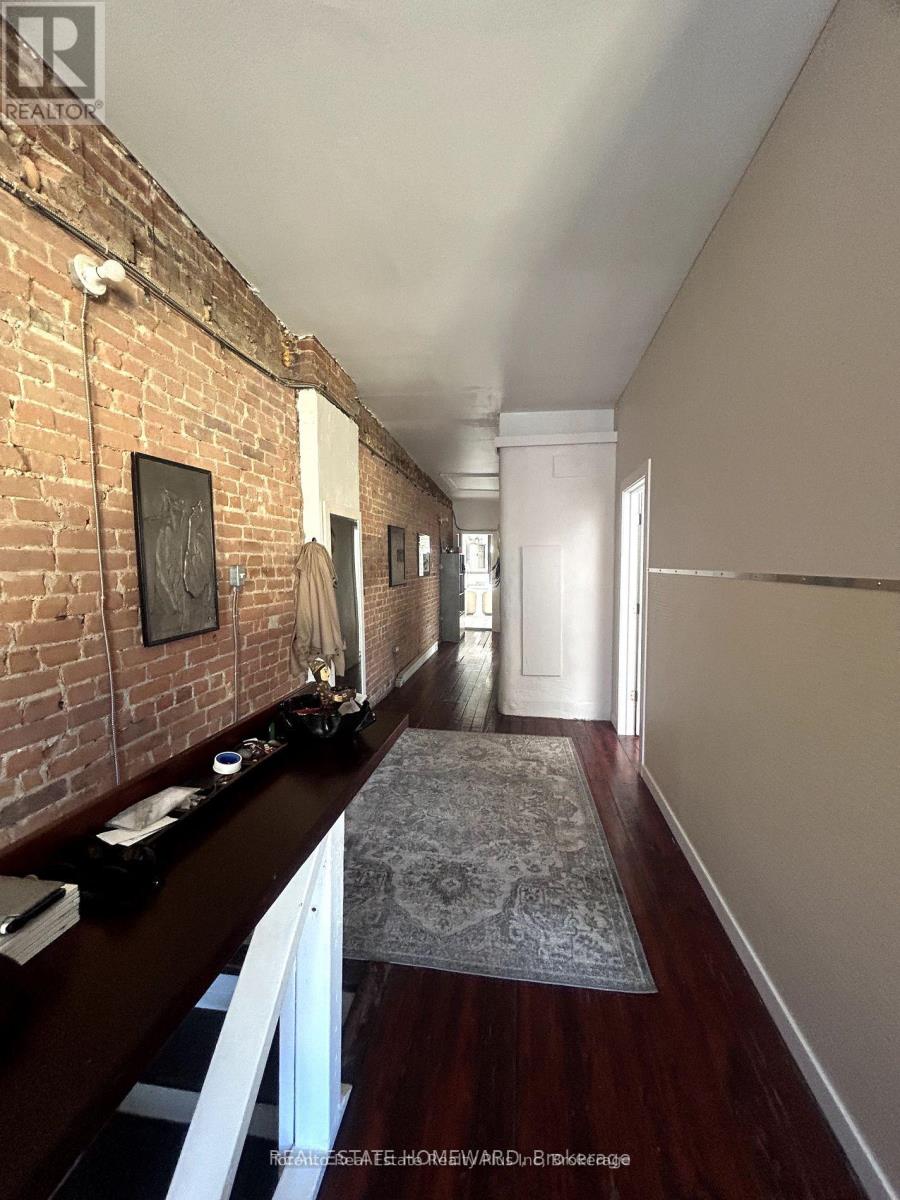 A long hallway with a brick wall on the left and a rug on the floor.
