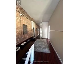 A long hallway with a brick wall on the left and a rug on the floor.