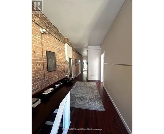 A long hallway with a brick wall on the left and a rug on the floor.