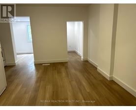 A room with wooden flooring and white walls.