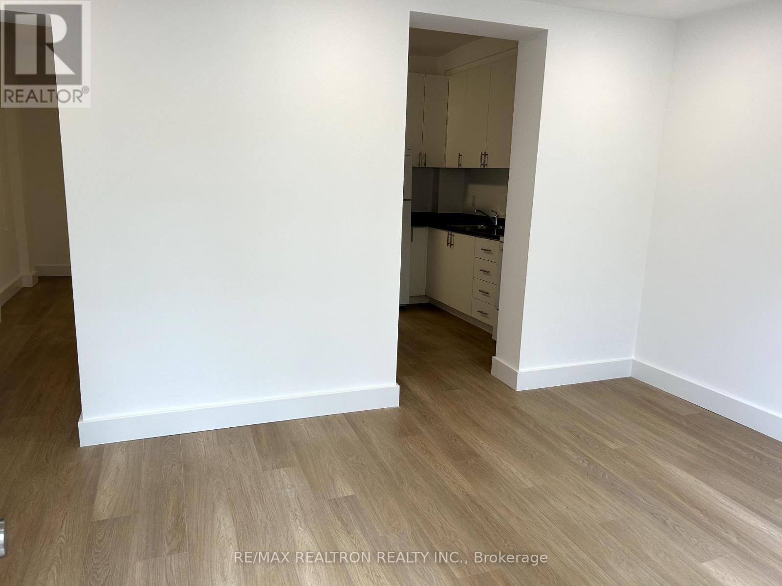 A room with a white wall and wooden flooring.