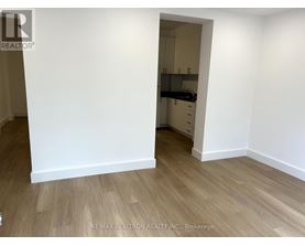 A room with a white wall and wooden flooring.