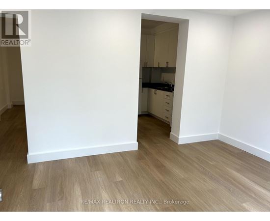 A room with a white wall and wooden flooring.