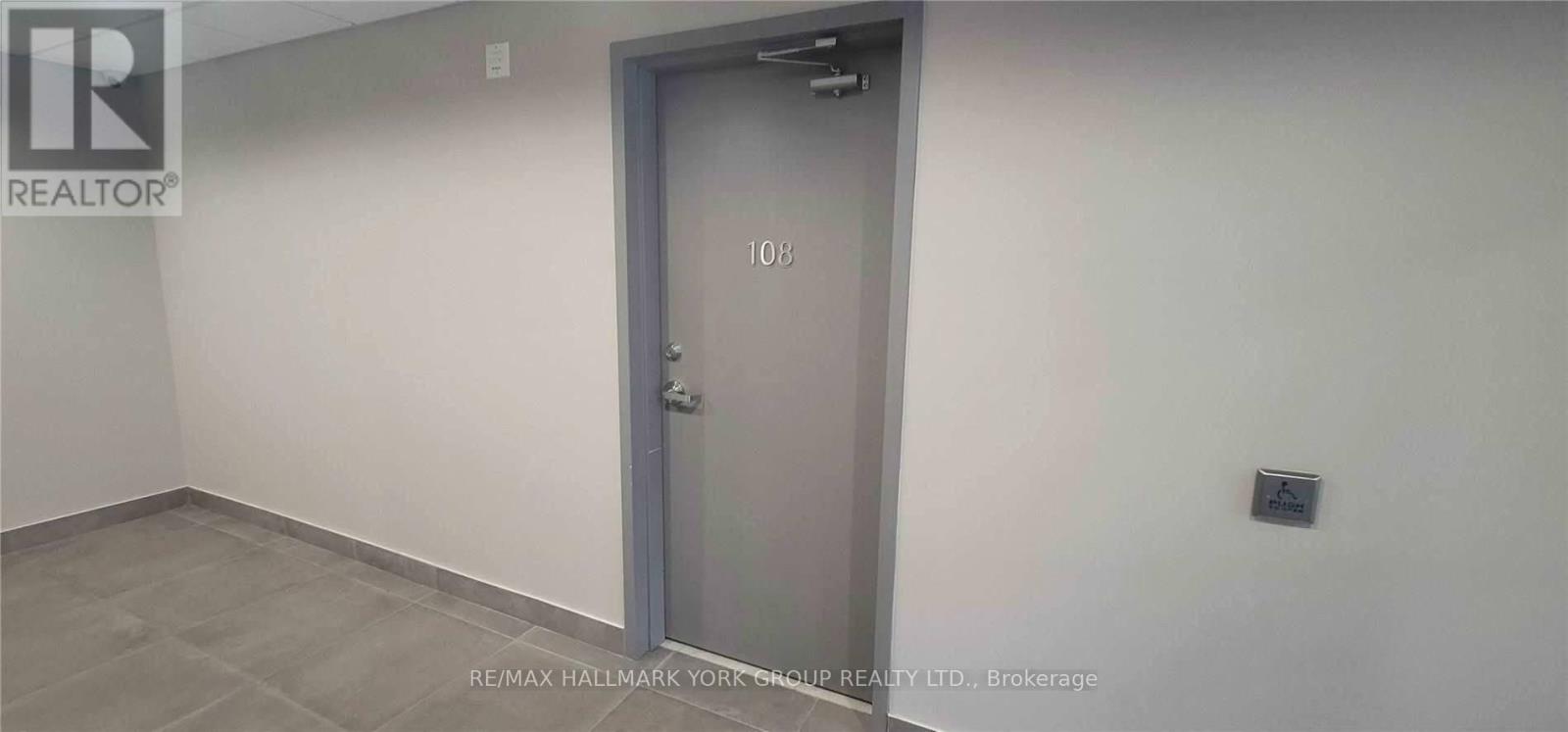 A room with a door numbered 103 and a brokerage sign on the wall.